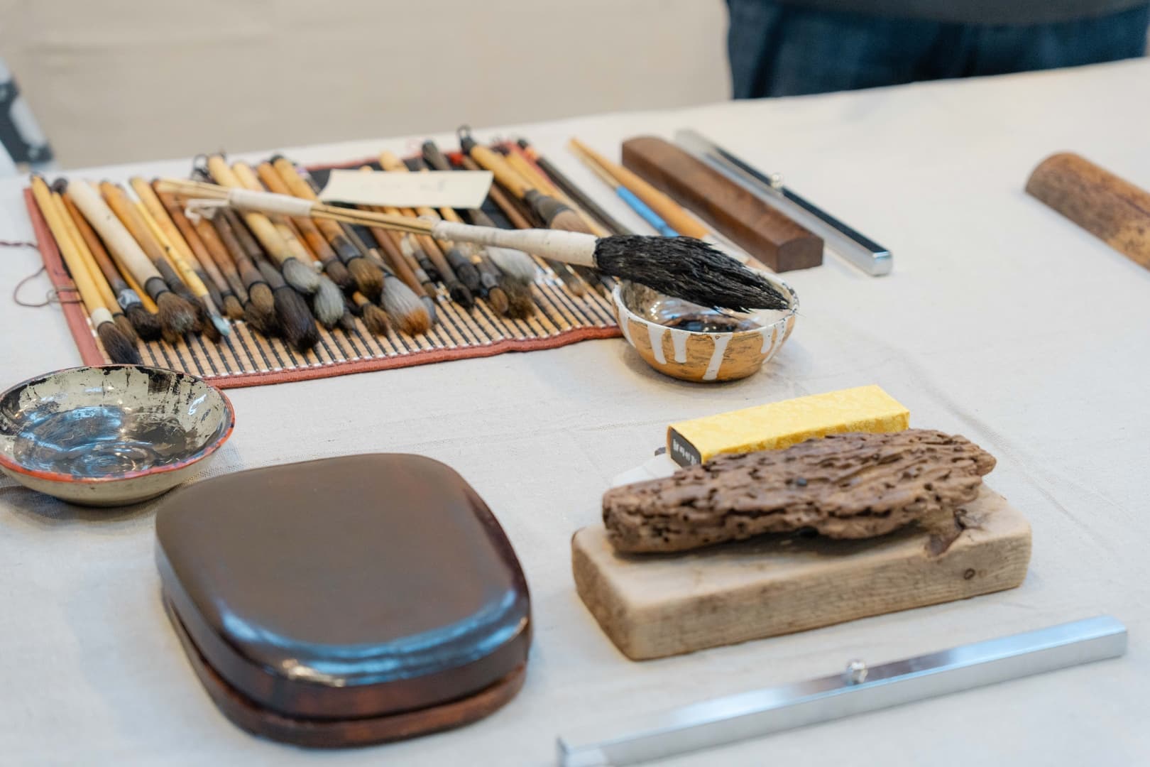 Various brushes, inks, and natural materials on a white table.