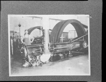 A man standing by part of a steam engine at Redlands Steam Plant