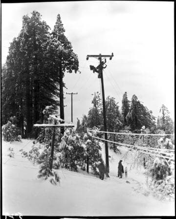 Linemen are replacing a lower distribution line that is nearly buried in snow with much taller one