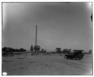 Erecting flagpole at Exposition Park [with gin pole