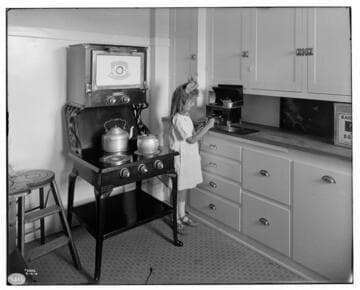 Hughes, Electric Range with little girl playing with toy stove on kitchen counter