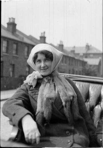 A young woman sitting in a carriage wearing a coat