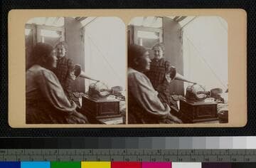 Ramona Lubo speaking into George Wharton James' graphophone, inside his wagon. Behind her is Mary Noble, a teacher at the Soboba Indian School