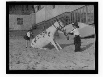 Two members of Meglin Kiddies with a mule on the beach at Gables Beach Club