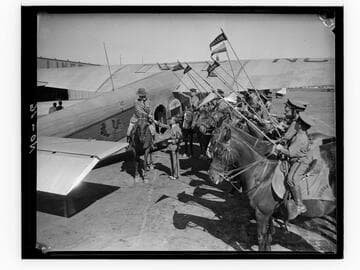 Urban Military Academy students on horses lined up next to TWA airplane