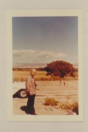 Dock Marston at the grave of Frank V. Goodman. The wooden markers in background are the graves of Nat Galloway and his wife