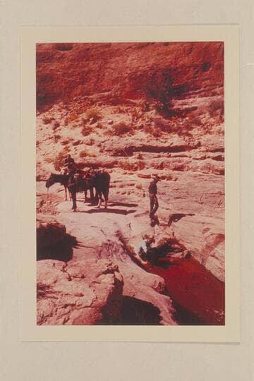 Water hole in Bald Rock Canyon.  Tom Daly crouches by the water.  Tobe Owl stands above him.  Christy Turner is on the horse