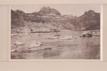 Bert Loper taking empty boat through lower part of No. 1 rapid at mouth of Piute Creek.  Chinle, Wingate, Todilto and Navajo from canyon wall.  Landslides in Chinle to right and left