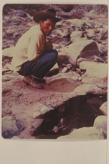 Bahe examines the clear and the black water in Black Water Creek just below Black Water Cave. North side of Navajo Mountain