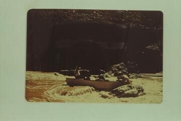 Miscue by George Wing on his first trip on San Juan River in 1947, May.Pat Reilly has stripped to his shorts and climbed out on the rock where he is jockeying the boat.Wing is pulling at the oars.When the punt was free, Reilly jumped back into it