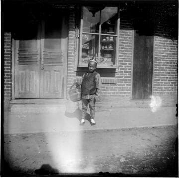 Boy standing in front of building, holding basket