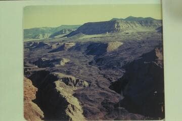 Whitmore Wash at lower left. Upper left is Mt. Trumbull, upper left center is Mt. Logan. The bosomy peaks of Mt. Emma are upper right. The road to the rim can be seen on the lava flow