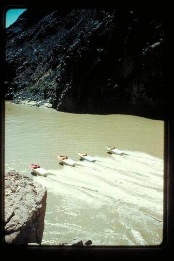 Four boats pass above Bright Angel Bridge