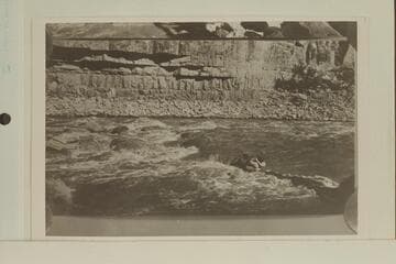 One of the Kolbs working out to the rock-locked boat in Dark Canyon Rapid. USGS Cataract Canyon survey under W. R. Chenoweth. Copy of small print loaned by Chenoweth. "Emery Going Out," Lint album