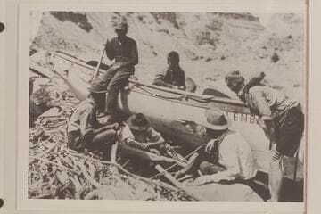 Part of the Eddy crew examining the hole punched in the "Dellenbaugh" while lining the 5th Rapid in Cataract Canyon. Upper: Holt Calloway, Lower: Felton with head down at left; McGregory; Eddy; Galloway; Marshall