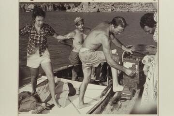 Nevills unloads the radio set which was recovered from the plateau below Point Sublime. John Doerr and Nancy Streator are back of him. The set was dropped to the 3 aviation men in 1944 when they parachuted into the Canyon