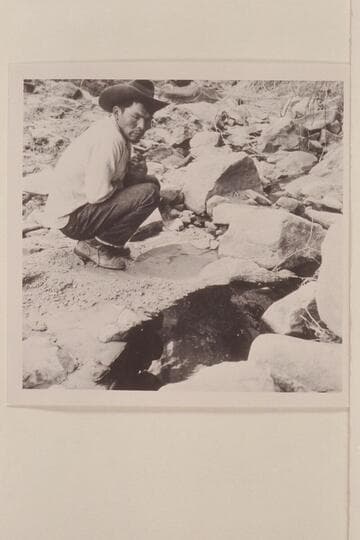 Bahe examines the clear and the black water in Black Water Creek just below Black Water Cave. North side of Navajo Mountain