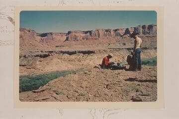 Across Labyrinth Canyon from above mouth of Horsethief Canyon.  Road down left bank is at edge of bototom.  A. C. Ekker watches Masland at his camera