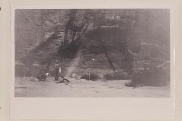 Bert Loper's Cave.  Loper is standing by the fire.  The figure on the bedroll appears to be Christensen.  Wright Bar opposite Navajo Creek, Colorado