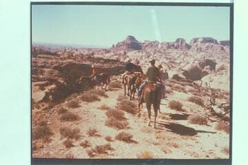 The party approaching ruined Rainbow Lodge after climbing out of Cliff Canyon. Tom Daly sits on the horse nearest the camera. Marston, Desloge and Atherton are right to left ahead of Tom. Octogon Mesa is upper center