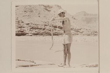 Garth Marston holds a rattler.  Mouth of the Little Colorado River.  Note the boulder island.  The canyon to the right is the beginning of the Grand Canyon