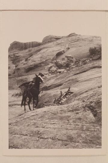Lehi mounts his horse as he tops the slick rock on the trail west of Nasja Creek