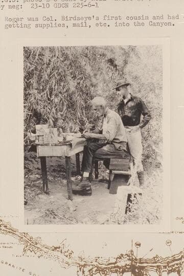 Col. Claude H. Birdseye at office work at Diamond Creek and watched by his cousin, Roger Birdseye