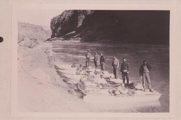 Pathe-Bray party below Lees Ferry. Eddy sits on the bow of the near boat. Boatmen from left to right are Daily, Woodbury, Rodin, Clark, Samoff, Dodge. Barber stands second from left; Kershnerr is second from right; LaRue is at right