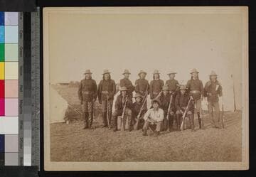 Group of Indian men in U.S. military uniforms at camp, holding rifles