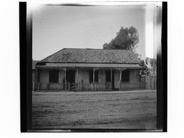 Adobe building with fence and sidewalk next to it