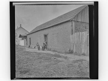 People outside the doorway of a large adobe building