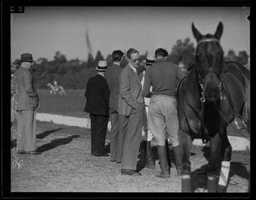 Leslie Howard standing next to polo field