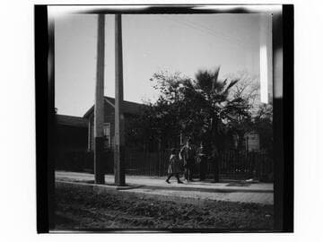 Three men and a girl on sidewalk with houses behind them