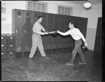 men striking a bowling ball with a baseball bat