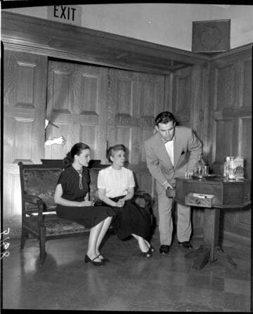 Actors on stage in drawing room while hands with a knife are pushing into the room