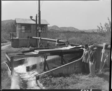Two men standing by an irrigation / filtering system (?)
