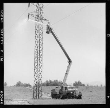 Lineman washing tower insulators from bucket with high pressure nozzle