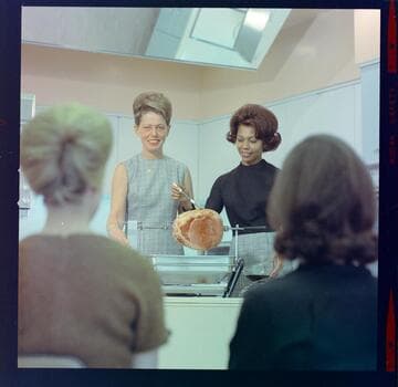 Home Economist Barbara Duffy and Karen Lindsay demonstrating electric rotisserie