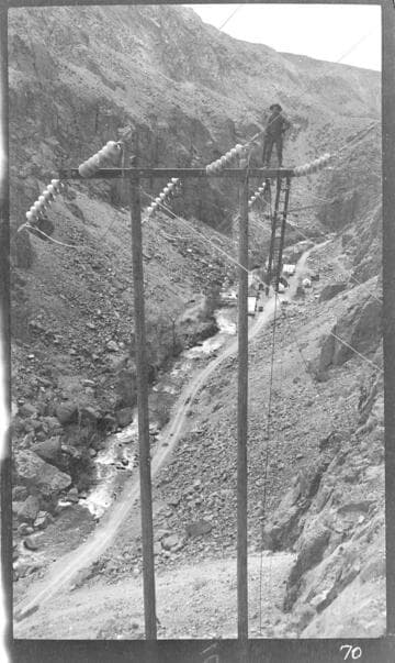 Man working on top of wooden H-frame transmission tower