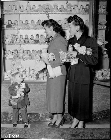 Two ladies and a little girl with two dolls at Christmas display