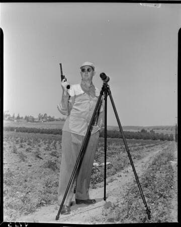 Man with pistol in field with spotting scope on tripod