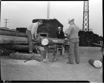 Men trimming the end off a pole
