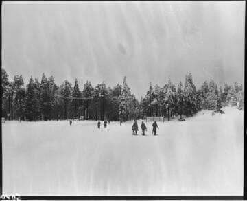 Group of men scattered out walking across snow field with snow shoes