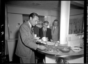 People sampling food from cooking demonstration in model kitchen