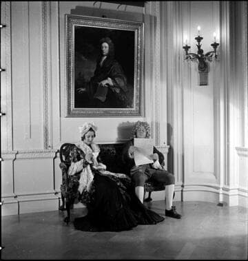 Costumed man & woman on settee below portrait of Robinson by Kneller in the Huntington residence
