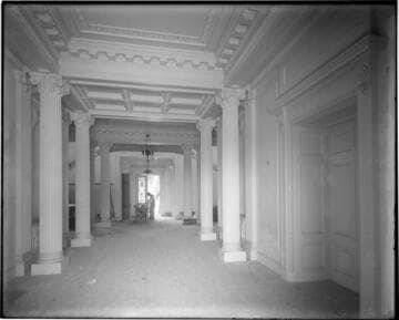 View of workman inside first floor hallway of the Huntington residence, circa 1910
