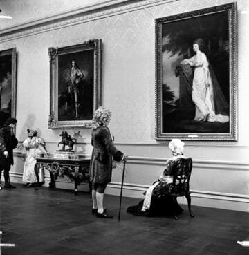 Four people in period costume in the portrait gallery in the Huntington residence