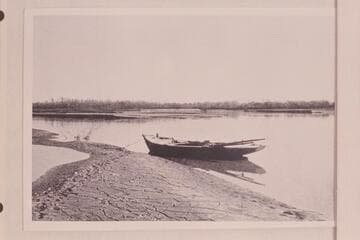Boat used by Sykes in the Delta.  Boat moored to edge of mud bank in slack water