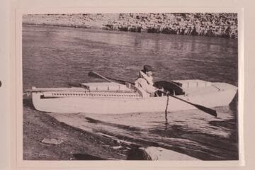 Ellsworth Kolb in boat used by USGS in survey of Cataract Canyon in 1921, Sep. Narrow beam was a handicap to stability. The forward bulkhead is so near the oarsman that he cannot make a full stroke of the oars. In Cataract Canyon