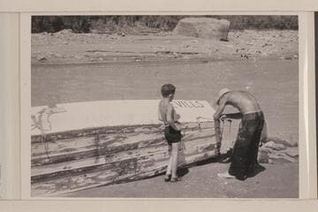 Norm Nevills repairing boat (?) after hitting rock; probably Nokai (?) Rapids. Jackie Frost watches